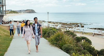 Couple walking along coastal walk overlooking Merewether beach